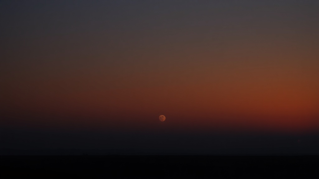 Übergang von tiefem Nachtblau zu warmem Morgenlicht über einer weiten Landschaft